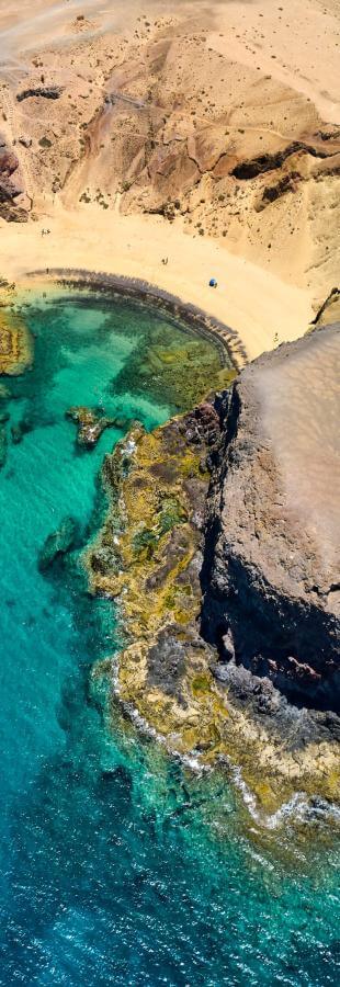 Näkymä Papagayo-rannalta Lanzarotella, kultaista hiekkaa, rantajyrkänteitä ja turkoosinsininen meri.